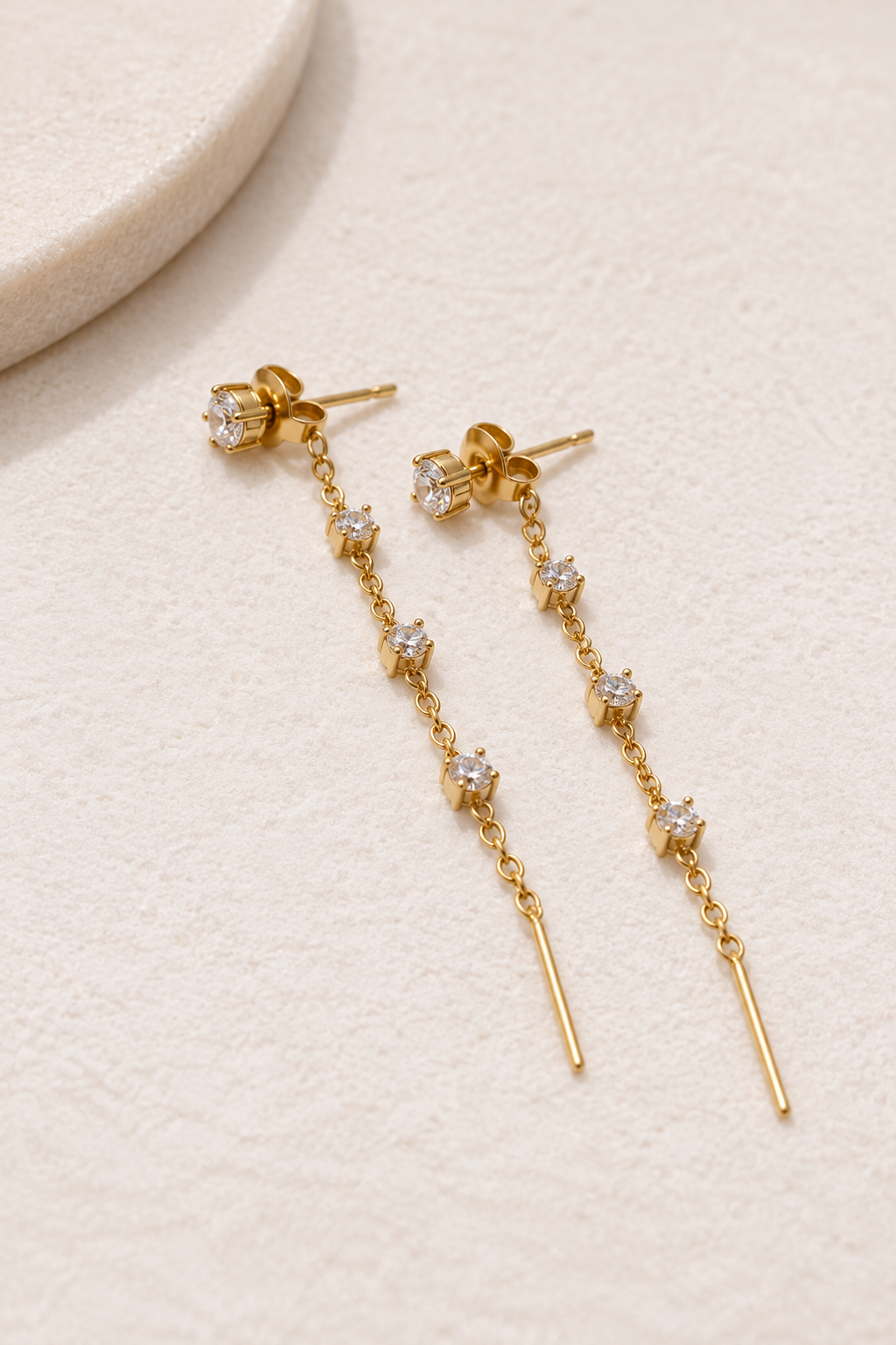 Boucles d’oreilles dorées pendantes Éclat avec pierres transparentes et chaîne au fermoir arrière