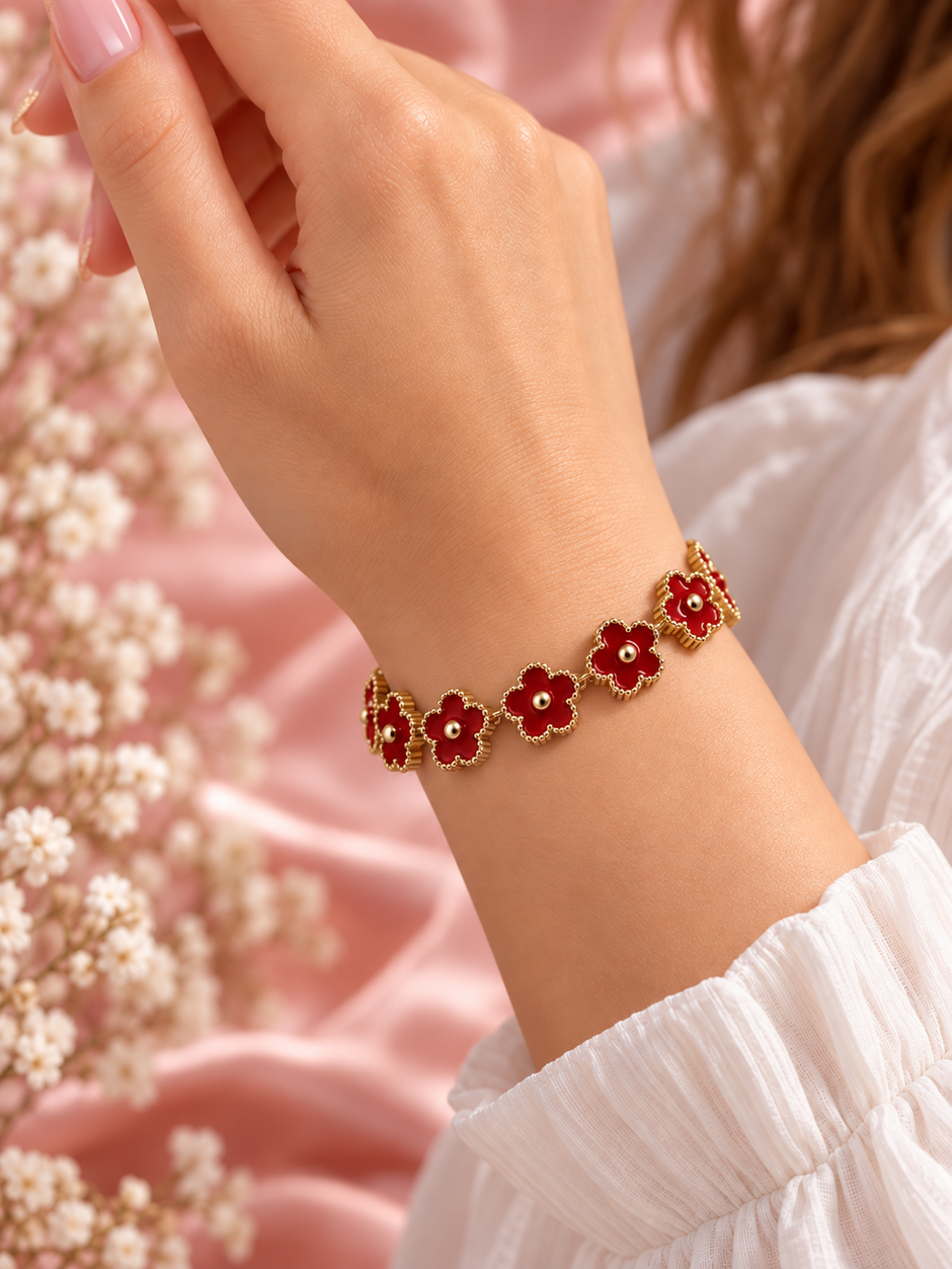 Bracelet Fleur doré à motifs floraux rouge, porté au poignet sur fond rose poudré – Secret de Rose bijoux