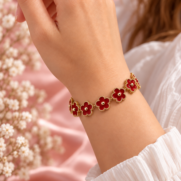 Bracelet Fleur doré à motifs floraux rouge, porté au poignet sur fond rose poudré – Secret de Rose bijoux