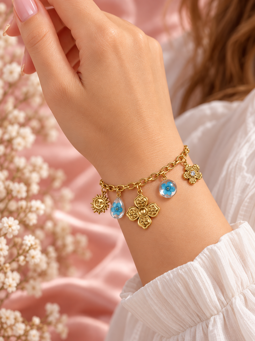 Bracelet Flora doré porté au poignet, breloques fleurs et soleil et deux ornements floraux bleus – Secret de Rose bijoux