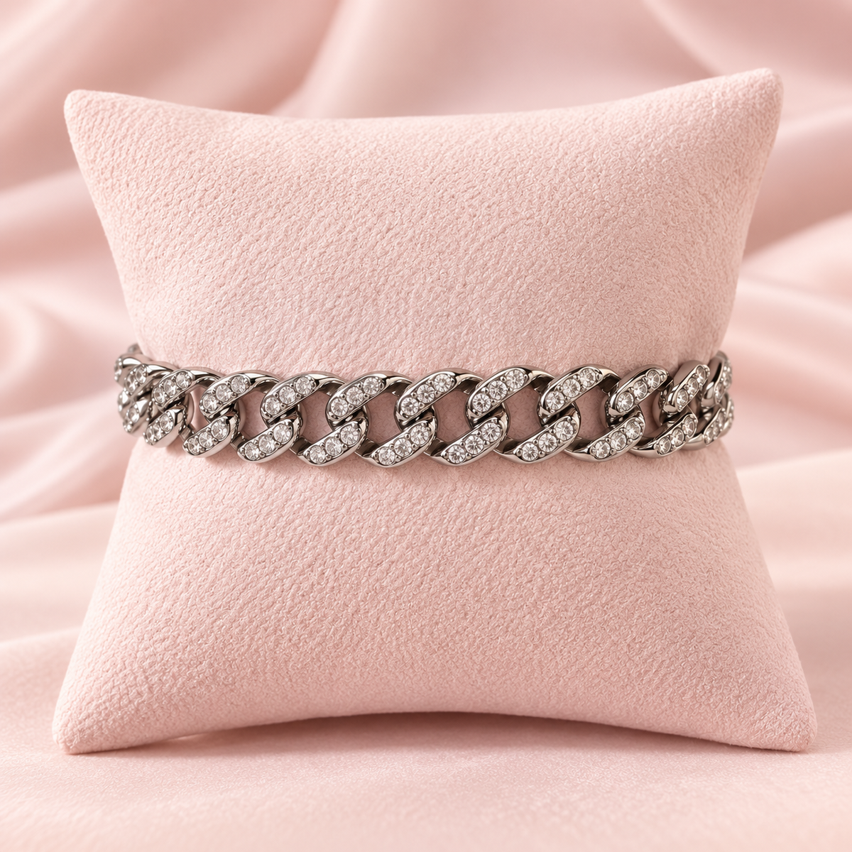 Bracelet maille gourmette argenté avec strass transparents sur un présentoir rose pâle