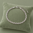 Bracelet maille tressée argenté modèle 0,6, 15 + 5 cm sur coussin vert sauge