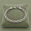 Bracelet maille tressée argenté modèle 1,6, 19 + 5 cm sur coussin vert sauge