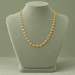 Collier grain de café doré, maille S, 45 cm, sur présentoir vert sauge