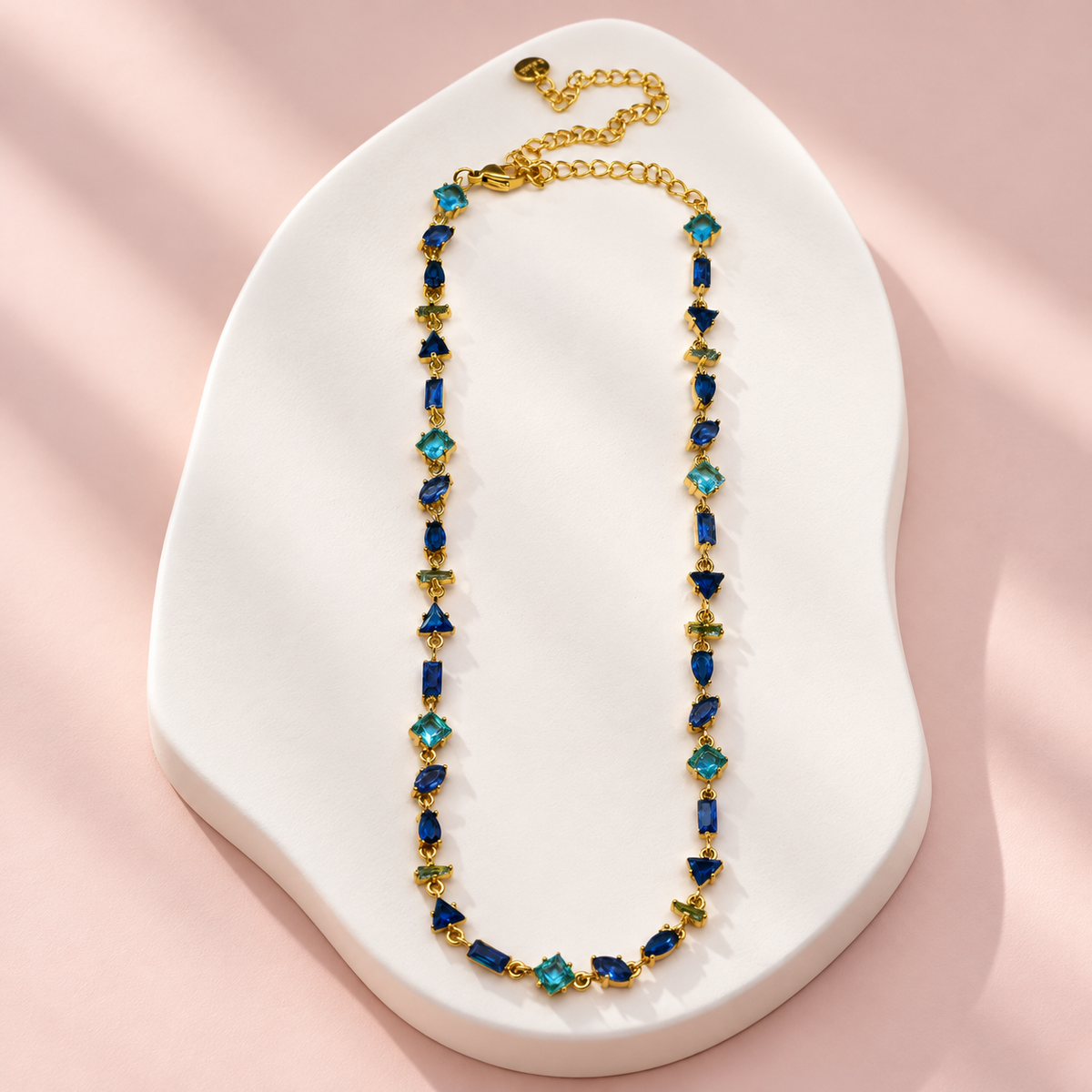 Collier Prisme en acier et strass – Doré – Bleu sur support blanc et fond rose