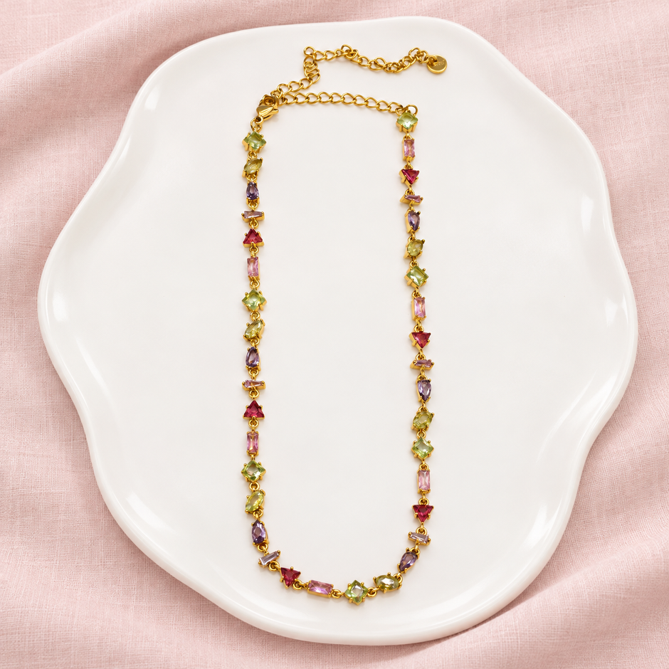 Collier Prisme en acier et strass – Doré – Multicolore sur support blanc et fond rose