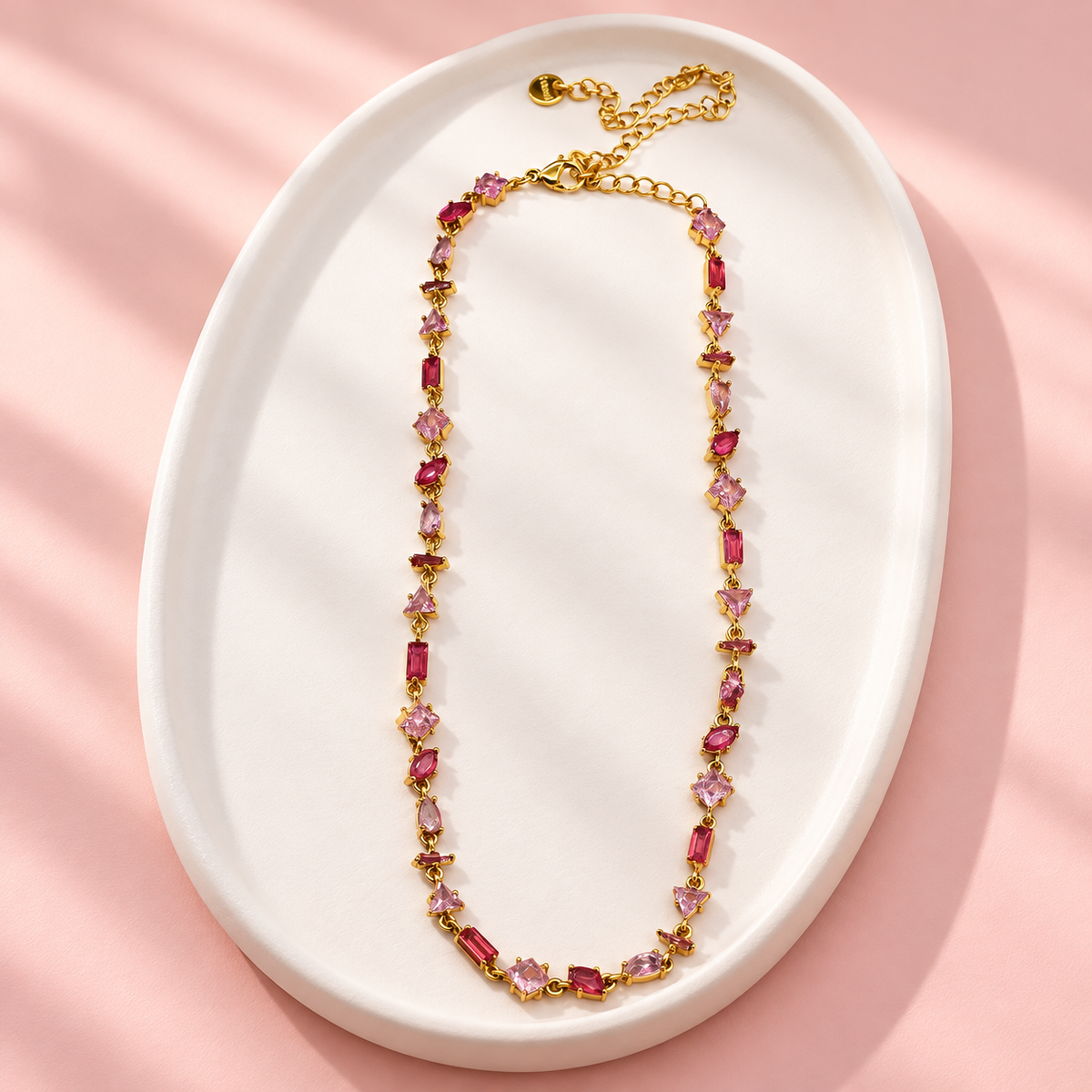 Collier Prisme en acier et strass – Doré – Rose sur support blanc et fond rose