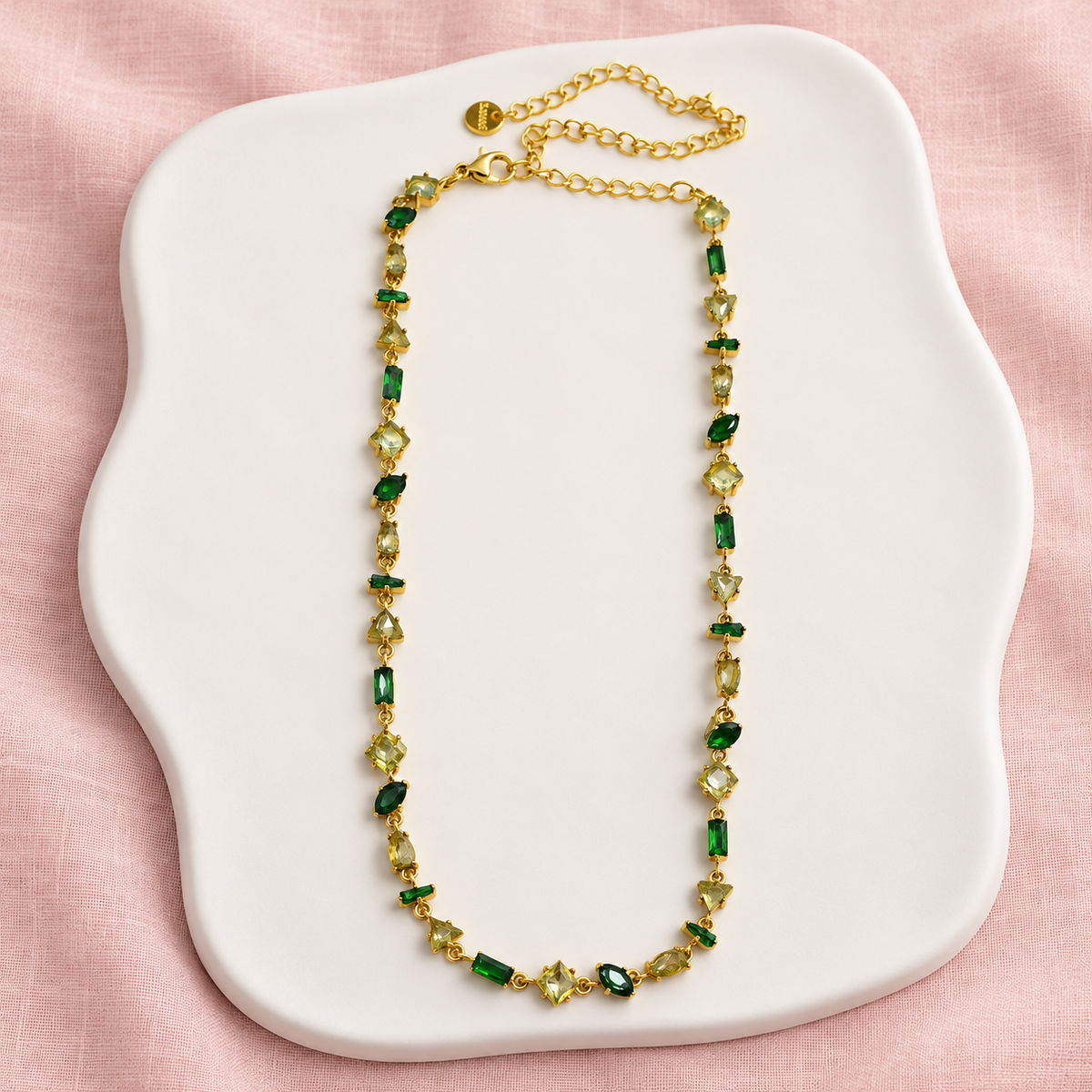 Collier Prisme en acier et strass – Doré – Vert sur support blanc et fond rose