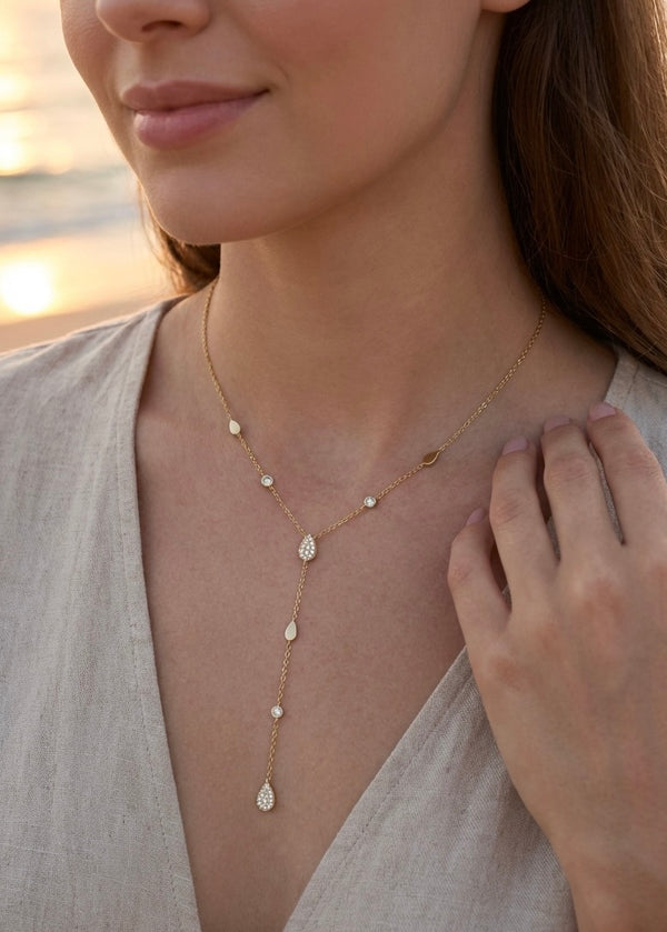 Collier doré en Y avec motifs gouttes et détails scintillants, porté sur femme