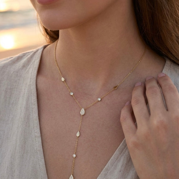 Collier doré en Y avec motifs gouttes et détails scintillants, porté sur femme