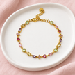 Gourmette Prisme en acier inoxydable et strass – Doré – Multicolore sur support blanc et fond rose