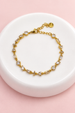 Gourmette Prisme en acier inoxydable et strass – Doré – Transparent sur support blanc et fond rose