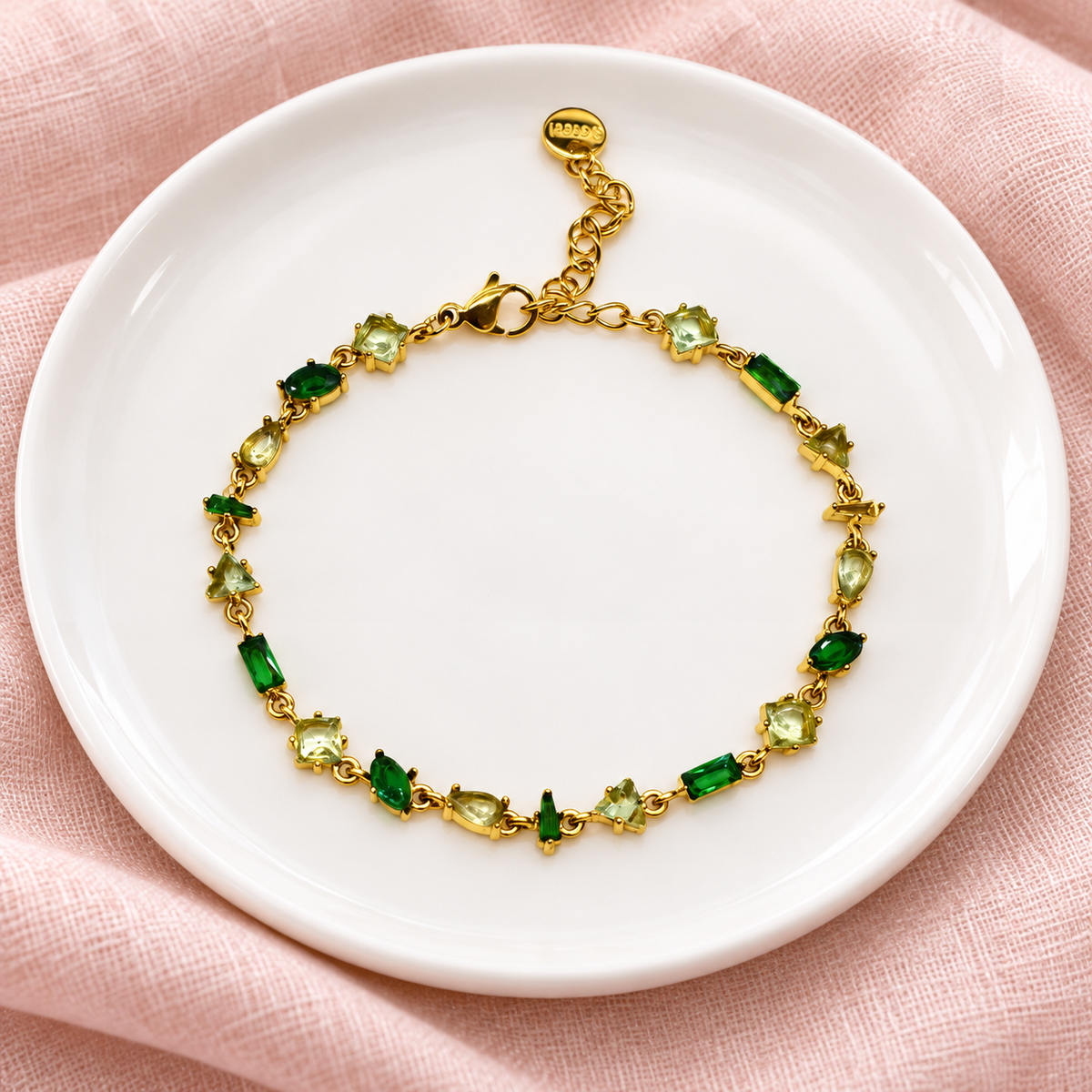 Gourmette Prisme en acier inoxydable et strass – Doré – Vert sur support blanc et fond rose