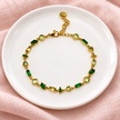 Gourmette Prisme en acier inoxydable et strass – Doré – Vert sur support blanc et fond rose